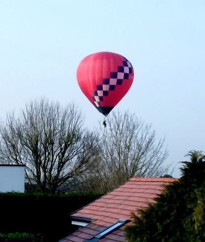 A red balloon flies low over the trees in Catshill
