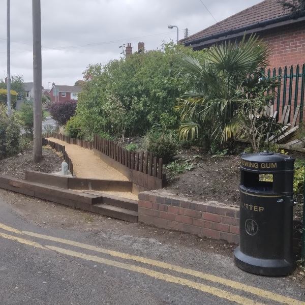 The memorial walk on the corner of Gibb lane and The Dock, Catshill, with plants and a yellowish path.